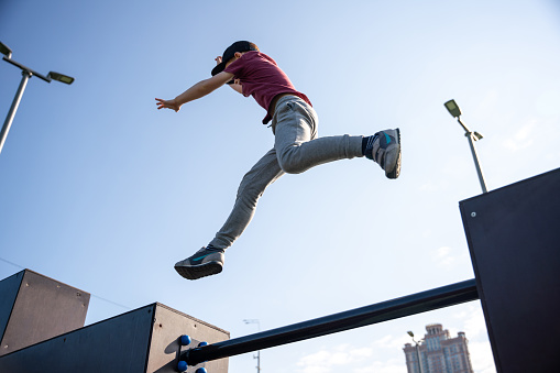 Boy jumping, parkour practice at sports ground in the morning