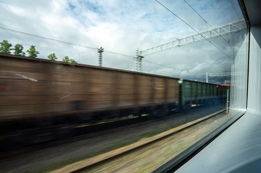 Freight train blurred in motion, view through the passenger train window