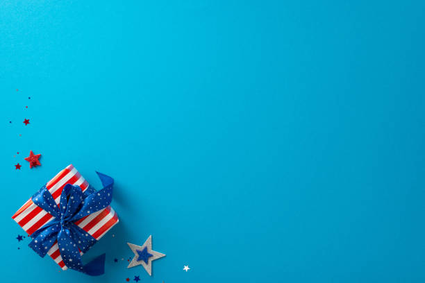 Celebrate USA's Independence Day with stunning top view perspective showcasing shimmering stars, confetti, giftbox wrapped in USA flag motifs, against blue backdrop that offers space for text or ad celebre el día de la independencia de ee. uu. con una impresionante perspectiva de vista superior que muestra estrellas brillantes, confeti, caja de regalo envuelta en motivos de la bandera de ee. uu., contra un fondo azul que ofrece espacio para texto o