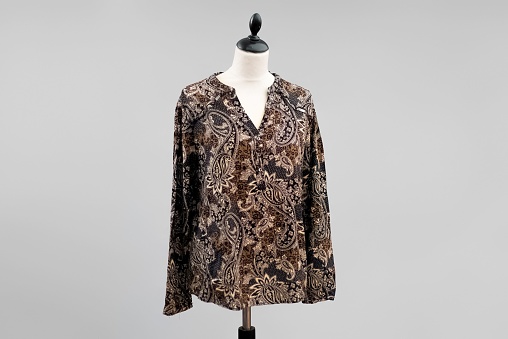 A stylish brown and beige blouse hanging on a headless mannequin