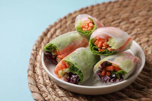 istock Plate of different delicious spring rolls wrapped in rice paper on light blue background, closeup 1499837677