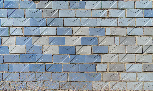 Old shabby textured wall is lined offset with old Soviet light blue and turquoise glossy ceramic tiles.