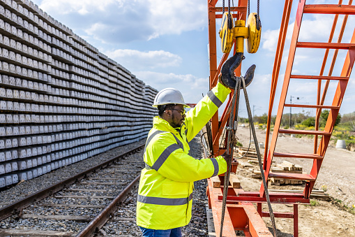 Construction worker working on a crane lifting heavy parts for railroad construction.