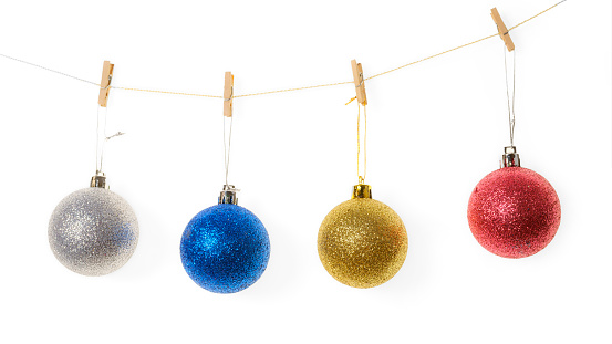 Four Christmas balls hanging on small wooden clothespins in a row. Isolated on white with clipping path