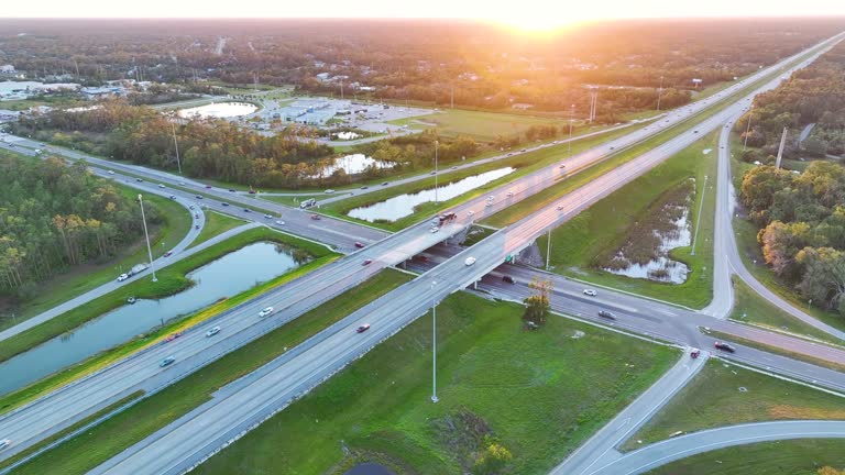 Elevated view of freeway exit junction over road lanes with fast moving traffic cars and trucks at sunrise. Interstate transportation infrastructure in USA