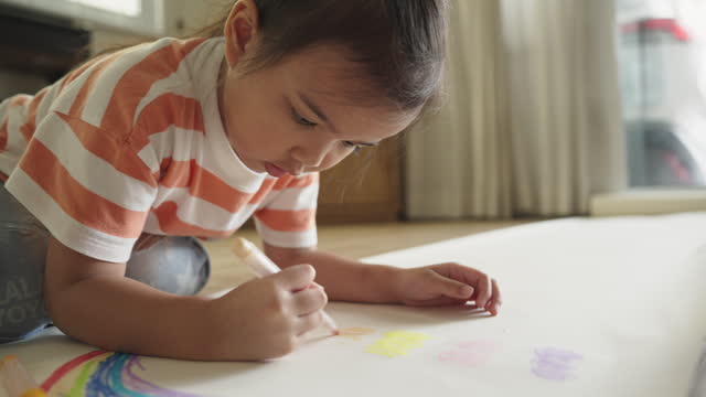 Asian little girl enjoys coloring and drawing on paper. Art education homeschooling