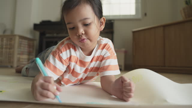 Asian little girl enjoys coloring and drawing on paper. Art education homeschooling
