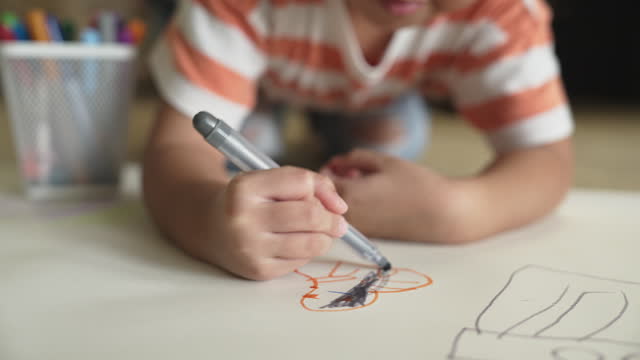 A girl drawing and coloring by felt tip pen at home