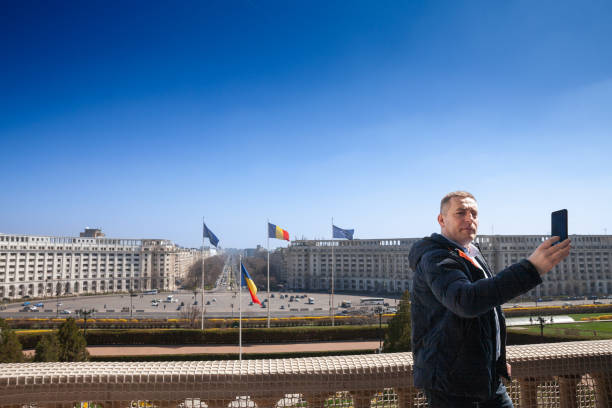 выборочное размытие на мужчине, делающем селфи перед площадью конституции румынии из румынского дворца парламента в бухаресте, символа ру� - constitutiei стоковые фото и изображения