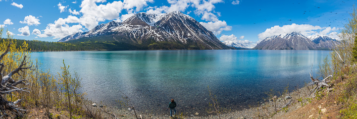 Stunning landscape beautiful view of Kathleen Lake in Yukon Territory, northern Canada with calm, pristine lake below snow capped mountain peaks in May, spring time.
