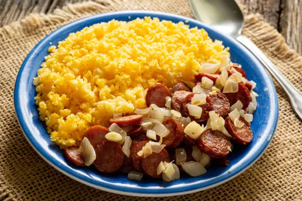 Dish of couscous "cuscuz brasil" "Cuscus,Cuzcuz,Cuscuz" with eggs and pepperoni butter, from the north and northeast of Brazil, typical food of Brazilian cuisine, on a rustic wooden table
