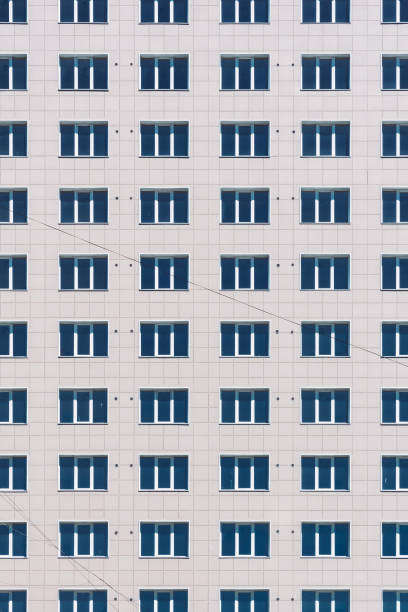 geometrischer hintergrund mit vielen fensterreihen. einfaches hochhaus in klassischem design. realistisches konzept des bürogebäudes. hintergrund, textur des mehrfamilienhauses. viele fenster an großen wänden in nahaufnahme. - architecture classic close up office building stock-fotos und bilder