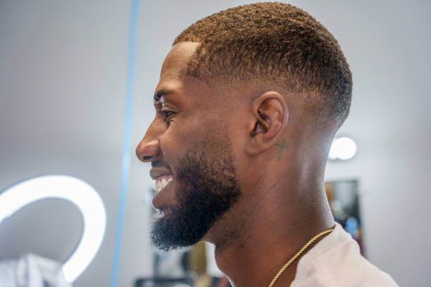 Young African American Man Receiving Fade Haircut from Mexican Barber in an Old Fashioned Barbershop with Electric Clippers Young African American Man Receiving Fade Haircut from Mexican Barber in an Old Fashioned Barbershop with Electric Clippers fade in stock pictures, royalty-free photos & images