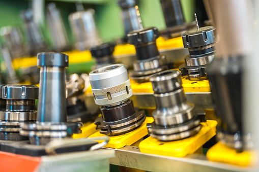 Close up on a holder attached to a CNC machine with many varieties of milling bits on.