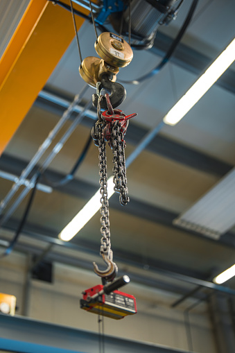 Metallic industrial hook with chains that is meant for lifting heavy things in a production facility.