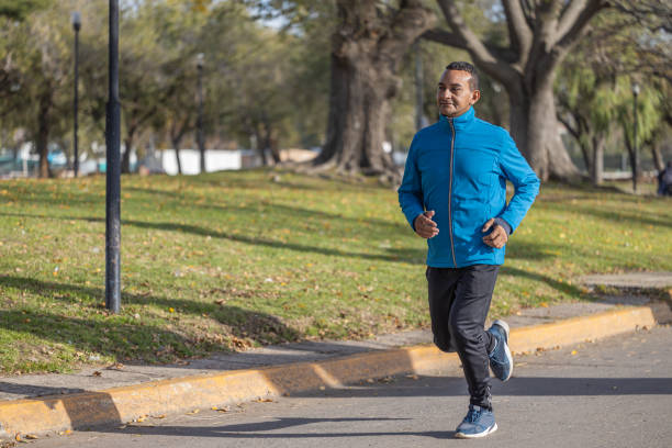 istock Young Latino man runs by a public park with copy space. 1499876700
