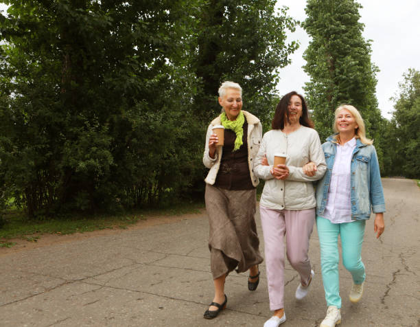 istock Three beautiful elderly women are walking in the park, having fun talking and drinking coffee. 1499877042