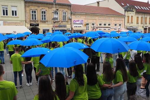 Sremska Mitrovica Serbia 05.19.23 Ball of graduates of schools on the central square. Youth performs a collective dance. Girls and boys wear green t-shirts. Dance with blue umbrellas. Prom degree day.