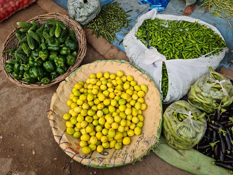 Okara Village Punjab, Pakistan -June 20th 2023- Photo of A group of baskets full of yellow and green vegetables.At the Top of center there is also a close-up shot of one lemon in particular.