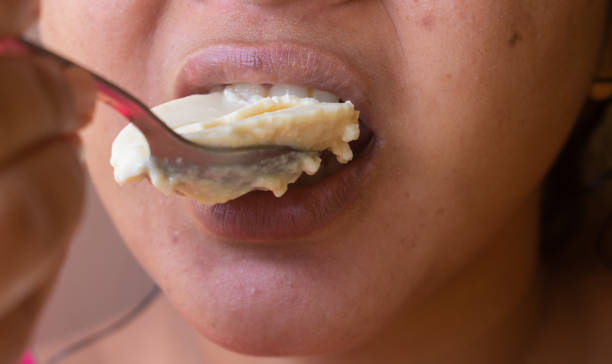 primer plano de una mujer india comiendo queso cuajado en la cocina. concepto de alimentación saludable y desintoxicación corporal. - cuajar fotografías e imágenes de stock