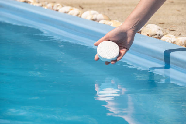 cropped shot of housekeeping holding chlorine tablets before throwing in swimming pool. - sewage pond imagens e fotografias de stock