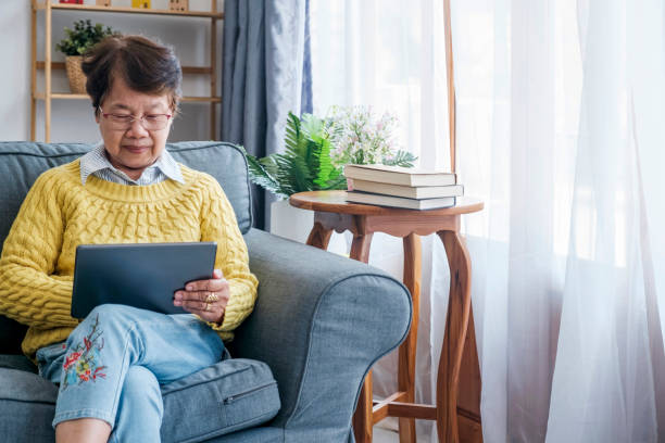 istock Mature Asian Woman Using Digital Tablet Sitting At Home 1499902519