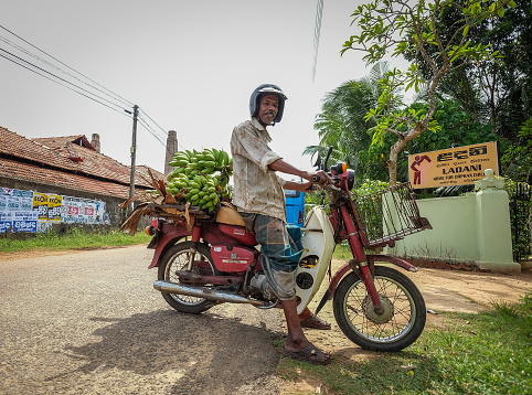 Colombo, Sri Lanka - Sep 8, 2015. A man carrying banana by scooter at countryside in Colombo, Sri Lanka.