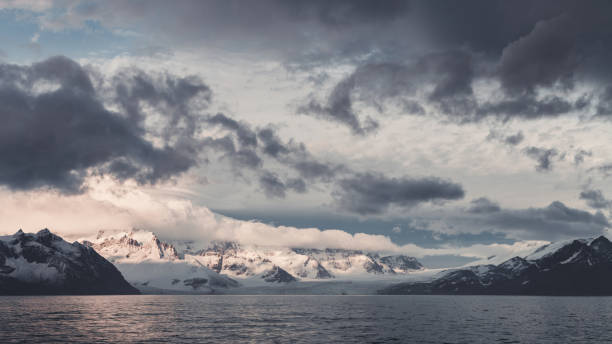 Antarctic Peninsula - Antarctic Ocean in moody Sunrise Twilight. Coastal view towards huge Glaciers and Mountain Range over the calm Antarctic Ocean - Antarctic Sound under colourful moody dawn skyscape. Antarctica Ocean - Antarctica Sound, Antartica Peninsula, Antarctica.