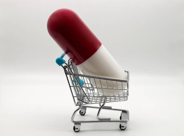 ショッピングカートの中の大きな薬のカプセル。薬物消費の増加の概念 - pill medicine capsule excess ストックフォトと画像