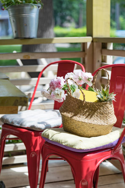 Straw wicker summer bag with a bouquet of pink flowers and a yellow notebook on the background of a cafe. Summer collection