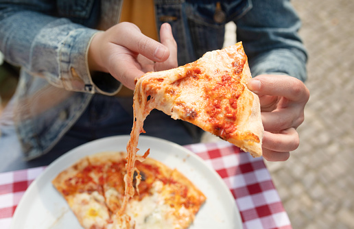 Hand grabbing slice of cheesy pizza. Hot pizza slice with melting cheese. Lunch or dinner delicious food italian traditional.