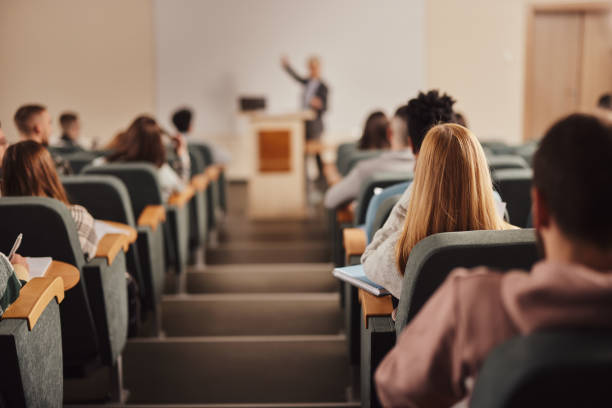 istock Rear view of large group of students on a class at lecture hall. 1499920838
