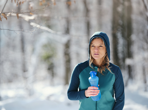 Athletic woman having a water break in winter day.