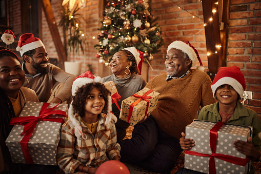 Happy African American multi-generation family with presents having fun on New Year's celebration at home.