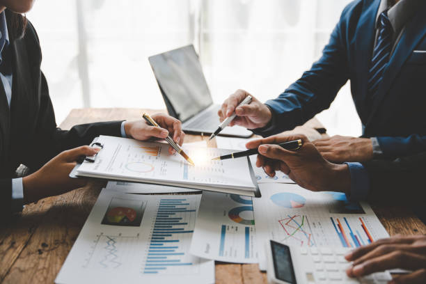 istock Young colleagues discuss business and analytical price charts using calculators and laptops to calculate financial, tax, accounting, statistics and analytical research ideas. 1499929296