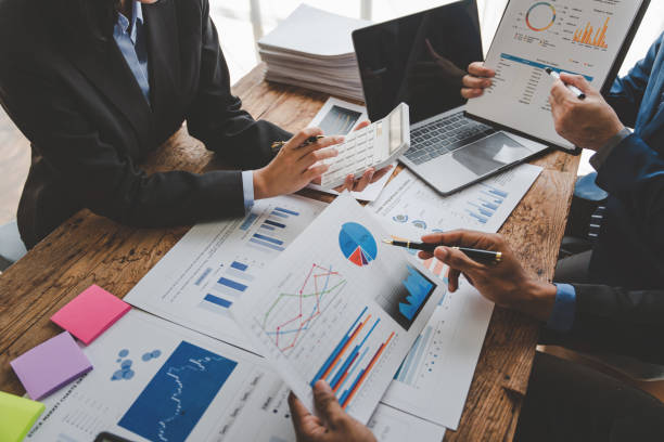 istock Young colleagues discuss business and analytical price charts using calculators and laptops to calculate financial, tax, accounting, statistics and analytical research ideas. 1499929383