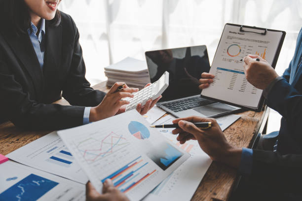 istock Young colleagues discuss business and analytical price charts using calculators and laptops to calculate financial, tax, accounting, statistics and analytical research ideas. 1499929385