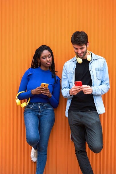 istock Woman and man using mobile phone standing against colour wall. 1499932675