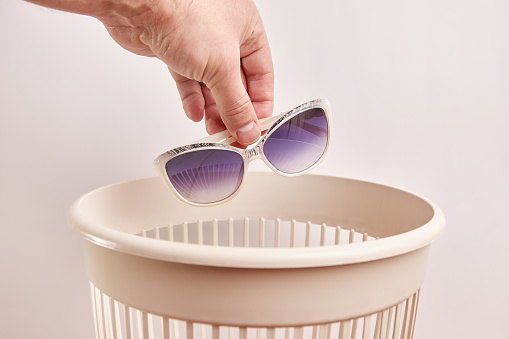 Plastic sunglasses are thrown into the trash. Disposal and recycling of plastic.