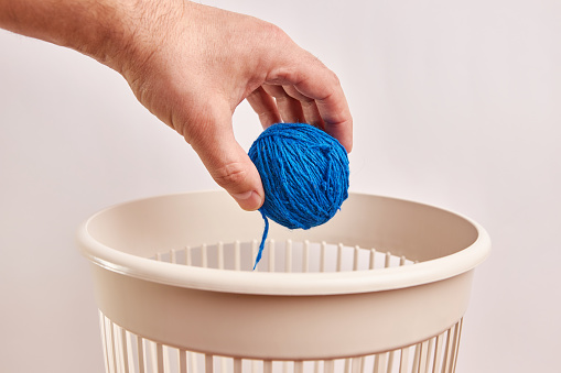 A ball of woolen threads is thrown into the trash. Disposal and recycling of waste.