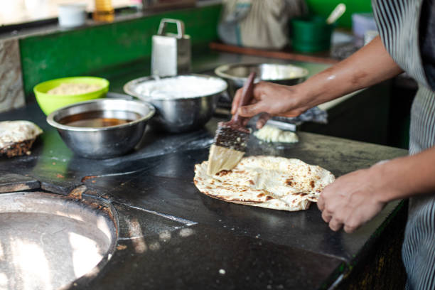 istock Cropped chef hands hold baking spatula, expertly cook dough or flatbread for shawarma at outdoor kitchen in food stall 1499935824