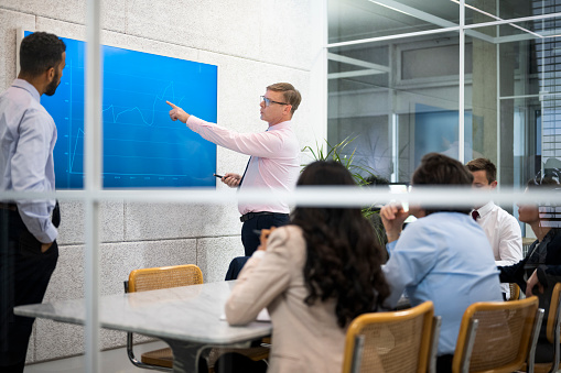 Businessman presenting graph while talking with team about business plan during meeting.