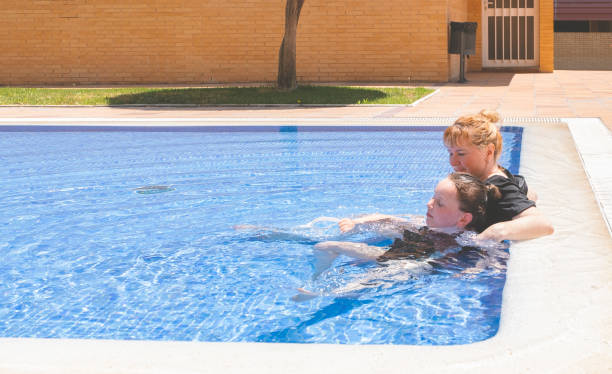 어린이, 7 세의 백인 소녀와 40 세의 여성이 태양을 즐기고 야외 수영장에 누워 있습니다. 여름 화창한 날. - female 8 9 years child excitement 뉴스 사진 이미지