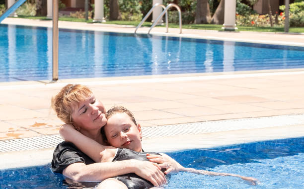 une femme de race blanche de 40 ans embrasse une fille de 7 ans, s’allonge dans une piscine extérieure et profite. journée ensoleillée d’été. - female 8 9 years child excitement photos et images de collection