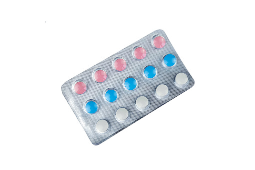 White blue red vitamins in blister isolated on white background with clipping path. Multicolored pills, top view