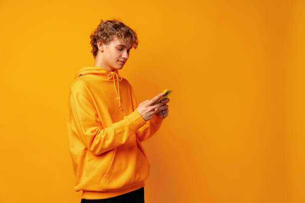istock Happy caucasian young man using smartphone against yellow background 1499943773