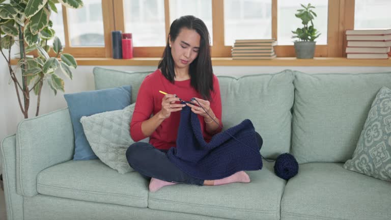 Woman knitting on sofa