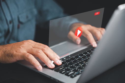 Man using a laptop to stream online videos. Conceptual image of streaming technology with a focus on the screen. Stay connected to the world of entertainment and learning.