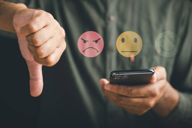 istock Unhappy client holding a mobile phone, displaying a thumb down sign with a graphic one-star icon 1499947896
