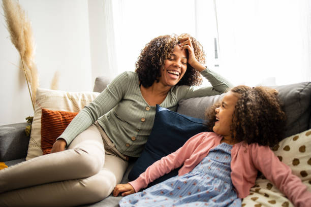 Mother and daughter at home talking Mother and daughter having fun in the living room good family stock pictures, royalty-free photos & images